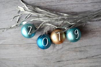 Christmas balls made of gold, turquoise and blue on a wooden background, decorated with a silver thread. Inscription 2019 New Year banner in the style of minimalism.
