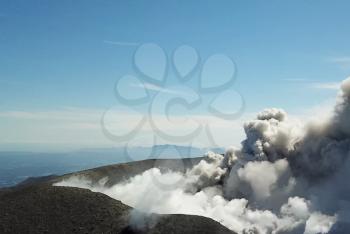 Smoke from the mouth of the volcano. Eruption. Clubs of smoke and ash in the atmosphere.