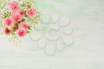 Pale pink roses and white flowers on light green background. Flowers  greeting card with place for text.