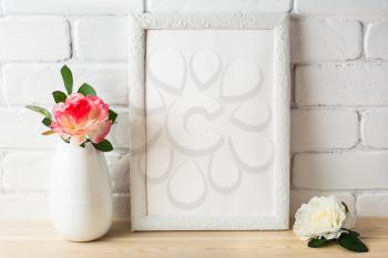 White frame mockup with pink and white roses. Portrait or poster white frame mockup. Empty white frame mockup for design presentation.