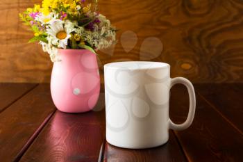 White coffee mug mockup with wild flowers. Empty mug mockup for product presentation. Coffee cup mock-up for promotion brand or design. 