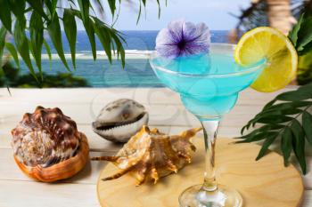 Blue Hawaiian cocktail on the tropical sea background. Iced blue cosmopolitan cocktail. Blue Lagoon cocktail. Blue margarita. Blue curacao liqueur. Iced blue cosmopolitan. Blue moon Cosmo martini