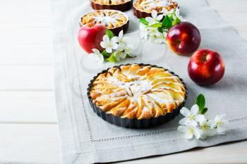 Sweet  apple pie with apple blossom. Homemade sweet apple slices pie on linen napkin with ripe apples and spring flowers.