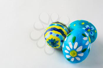 Blue hand-painted Easter eggs with floral design on a white background. Easter background. Easter symbol. Copy space
