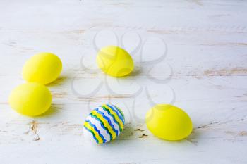 Decorated Easter white blue yellow eggs on a white wooden background, space for text, copy space