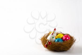 Decorative Hen in a nest with painted Easter eggs on a white background. Easter background. Easter background. Easter symbol. Copy space