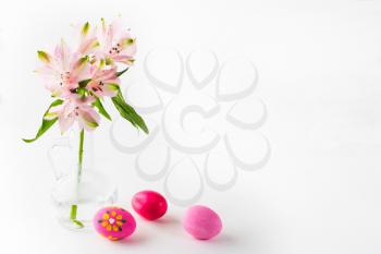 Hand-painted pink Easter eggs with light delicate pink flowers in a glass vase on white background. Easter background. Easter symbol. Top view with copy space. Horizontal