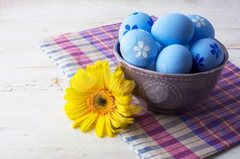 Light blue decorated Easter eggs in a purple bowl on a white wooden background. Easter background. Easter eggs. Easter. Easter hunt. Easter symbol.  Easter card. Easter greetings. Happy Easter