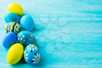 Row of blue hand-painted Easter eggs on blue wood plank. Easter background. Easter symbol. Top view with copy space