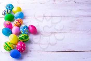 Row of multicolored hand-painted Easter eggs on white wood plank. Easter background. Easter symbol. Top view with copy space