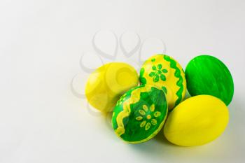 Yellow and green hand-painted Easter eggs with floral design on a white background. Easter background. Easter symbol. Copy space