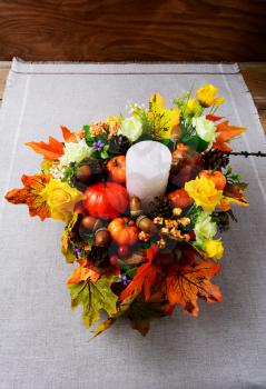 Fall decoration with candle and silk maple leaves, vertical. Thanksgiving greeting with fall decor. Fall centerpiece. Thanksgiving background.