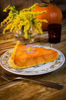 Pumpkin pie slice on the rustic  wooden table. Traditional Thanksgiving pumpkin pastry. Squash pie slice. 