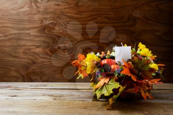 Thanksgiving decoration with silk fall leaves on rustic background. Thanksgiving greeting with fall decor. Fall centerpiece. Thanksgiving background. Copy space.