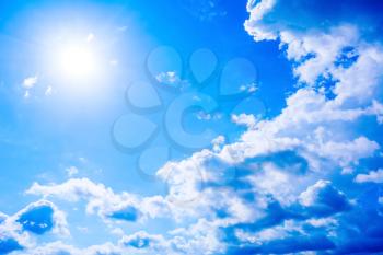 Cear blue sky with fluffy clouds and sunbeams. Beautiful cloudy blue sky background