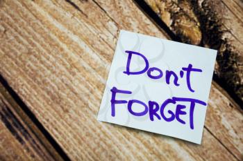 Handwritten Do not forget postive and motivational message on the white paper with retro wooden bark background. Motivational handwritten message on the white paper. 