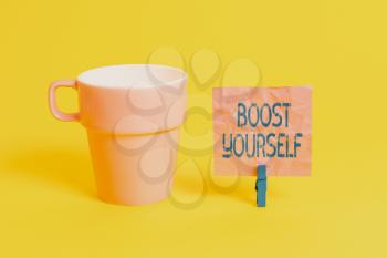 Text sign showing Boost Yourself. Business photo showcasing to make yourelf feel more positive or more confident Cup empty paper blue clothespin rectangle shaped reminder yellow office