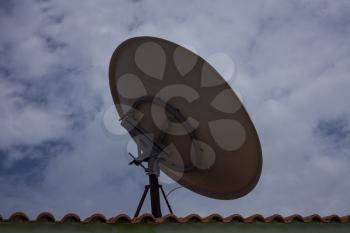 Parabolic dish antenna held on the roof top of a building. It is used by consumers to receive direct-broadcast satellite television from a direct broadcast satellite in geostationary orbit.