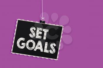 Text sign showing Set Goals. Conceptual photo Defining or achieving something in the future based on plan Hanging blackboard message communication information sign purple background