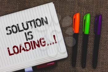 Text sign showing Solution Is Loading.... Conceptual photo thinking of way to solve big problems Diagnoses Open notebook page jute background colorful markers Expressing ideas