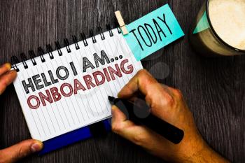 Word writing text Hello I Am... Onboarding. Business concept for telling person that you are on ship or plane Man holding marker notebook clothespin hold reminder coffee cup wood table