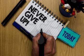 Writing note showing Never Give Up. Business photo showcasing Keep trying until you succeed follow your dreams goals Man holding marker notebook clothespin reminder wooden table markers