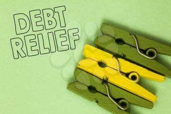Text sign showing Debt Relief. Conceptual photo partial or total remission of it especially those by countries Three green yellow vintage clothespins clear background Holding things