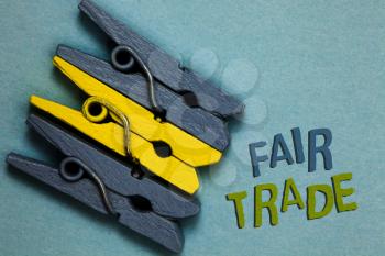 Conceptual hand writing showing Fair Trade. Business photo text Small increase by a manufacturer what they paid to a producer Gray yellow vintage clothespins clear background Holding things