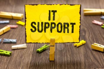 Text sign showing It Support. Conceptual photo Lending help about information technologies and relative issues Clothespin holding yellow paper note several clothespins wooden floor