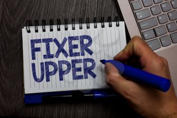 Writing note showing Fixer Upper. Business photo showcasing house in need of repairs used chiefly connection with purchase Man holding marker spiral notebook computer keyboard wooden background