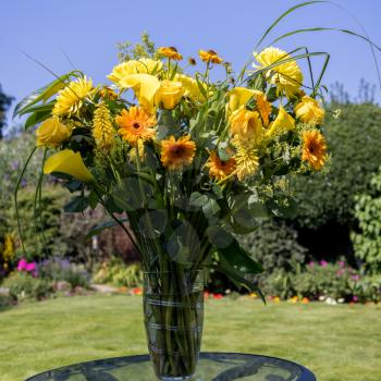 Yellow flowers in a vase on a garden table