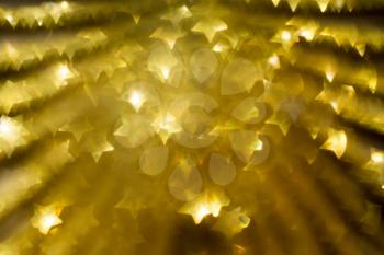 Festive background with defocused golden glitters, bokeh in a shape of a star.