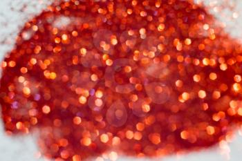 Defocused glitter as background with circular bokeh of red color.