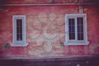 Old walls with cracked plaster and two windows.
