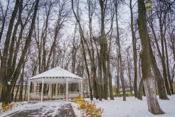 Decorative wooden alcove with benches in the city park at the winter time.