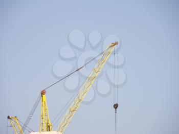 Crane and building construction site against blue sky.