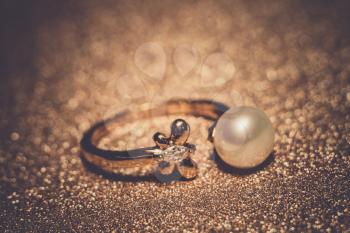 Luxury rose gold plated ring with freshwater pearl of white color, filtered background.