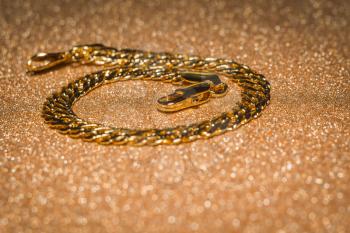 Fashion bracelet made of decorative gold chains background.