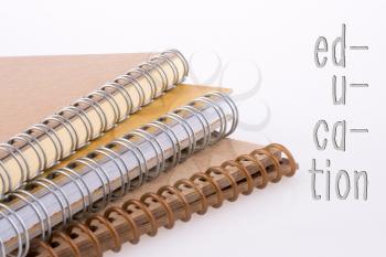 Education wording beside spiral notebooks on a white background