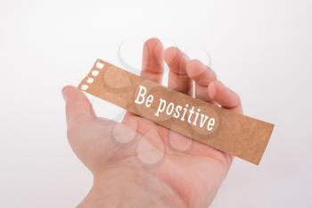 Hand holding torn notepaper with  be Positive thinking concept label