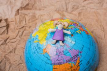 Miniature girl on top of globe as education and business concept