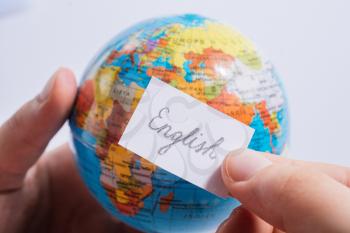 Hand holding notepaper with English wording on model globe