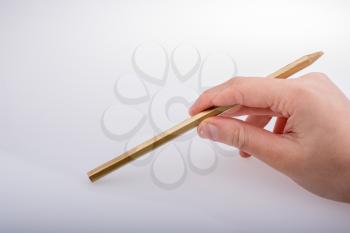 Hand holding a gold color pencil on a white background