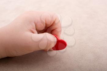 Little red color heart shape in hand on light brown background