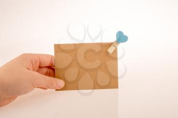 hand holding a paper placed in a clothespin withe heart on a white background