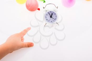 Hand pointing an alarm clock  with balloons on the white background