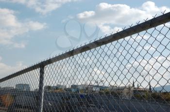 Cityscape through chain link fence. Highway barrier above the motorway.