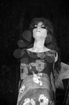 Plastic mannequin doll behind stained window of abandoned store. Black and white.