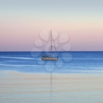 Sailboat reflections on sea water. Sunset sea and sky horizon.