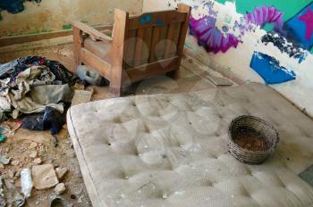 Dirty mattress and clothes on the floor of an abandoned house.